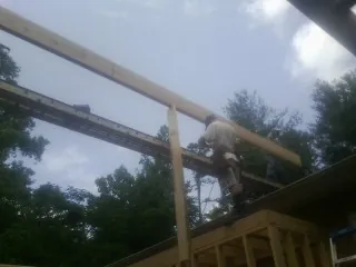 Carpenter setting a ridge beam over a new addition frame — Ice Dam Removal by Roofing Brothers in Camas Valley