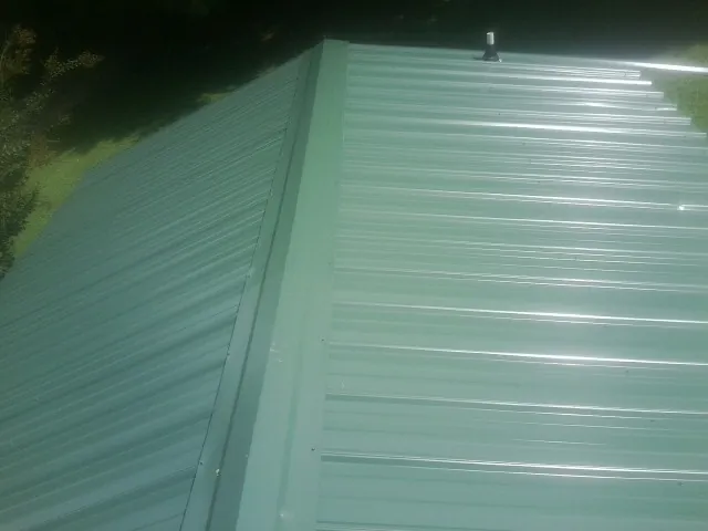 New green metal panels meeting at the ridge of a roof — Flat Roof Repair work by our crew in Camas Valley