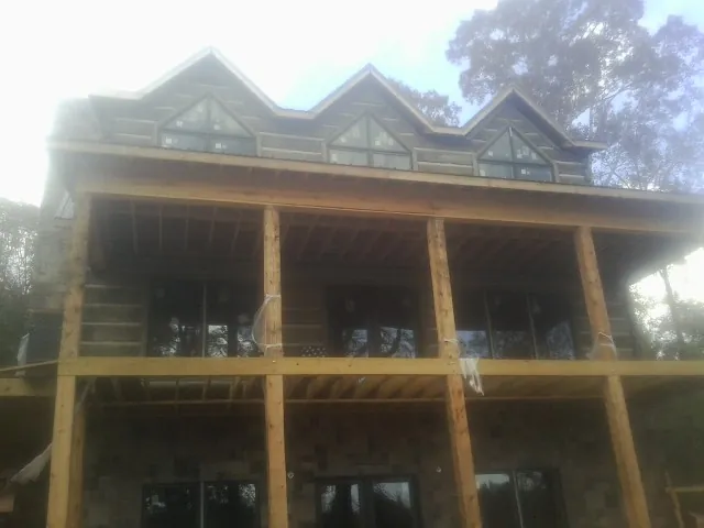 Dormers and porch framing on a large log home under construction — Roof Coating work by our crew in Camas Valley