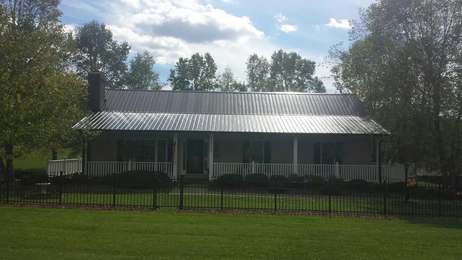Gray metal roof on a brick ranch with a full width front porch — Gutter Guard Installation work by our crew in Camas Valley