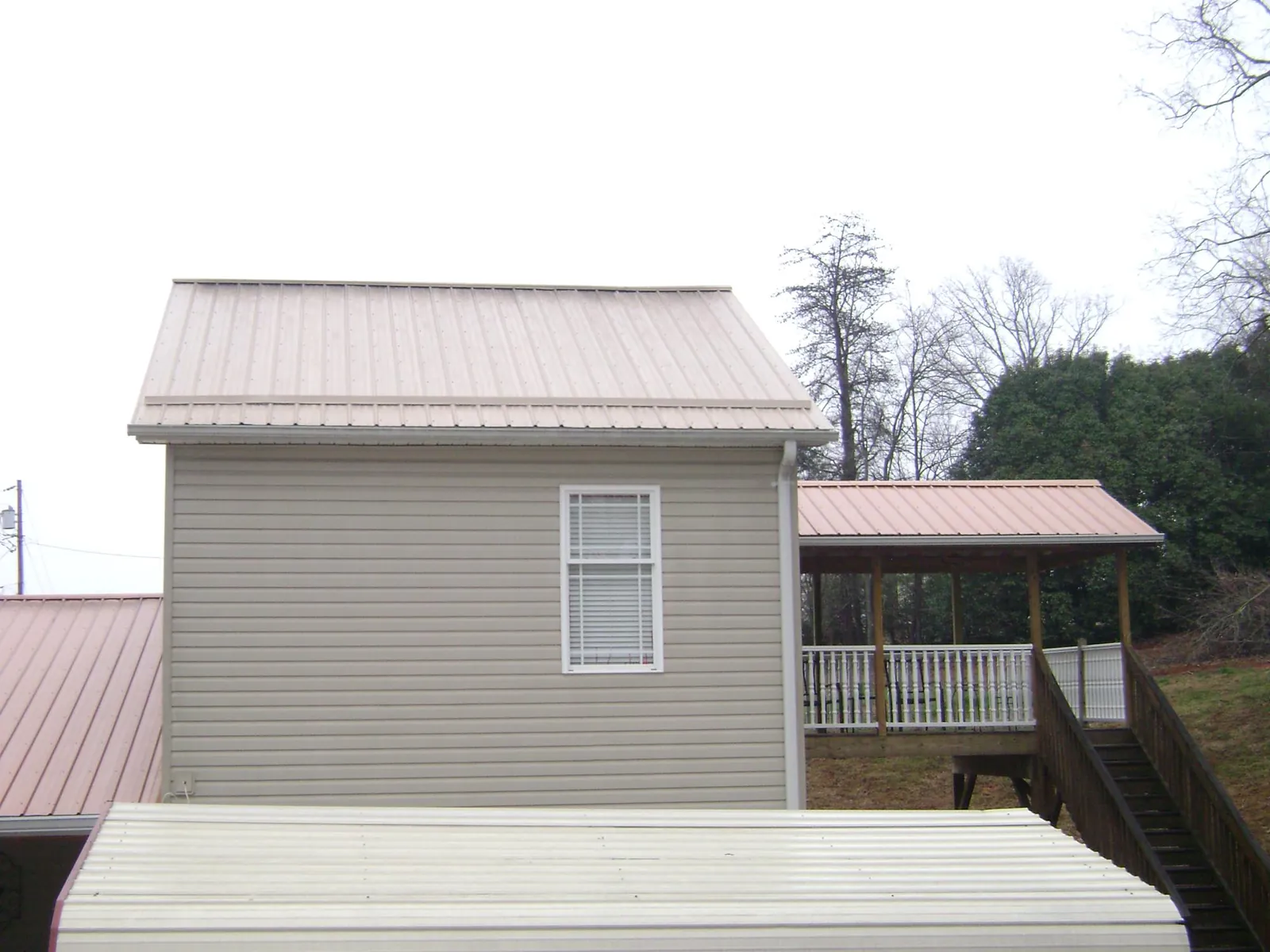 Tan metal roofs on a two story addition and attached porch, from a Roof Replacement job in Camas Valley