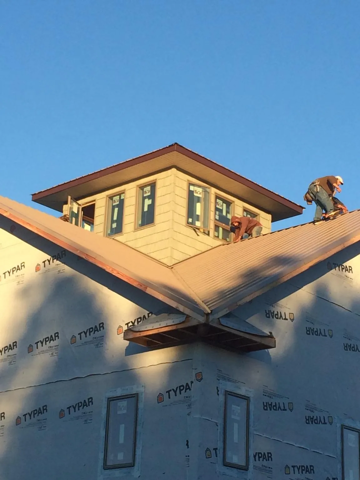 Roofers working around a rooftop cupola on a new metal roof at sunset — Roof Waterproofing in Camas Valley by Roofing Brothers